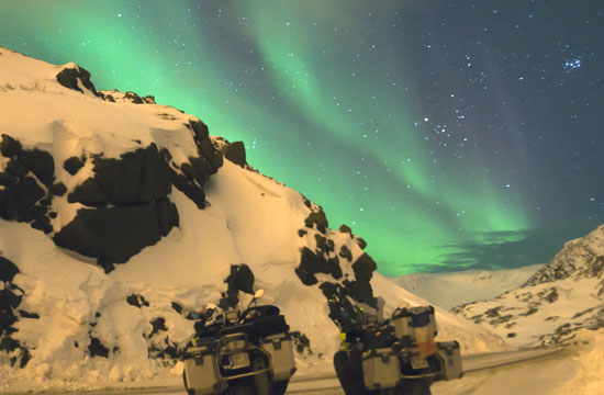 Bikes bask in the aurora borealis light.