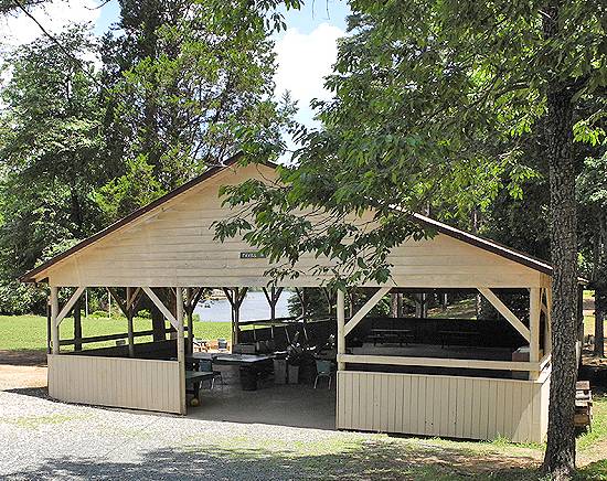 Exterior of large pavilion with lake in the background.